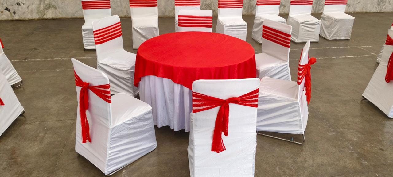 Round banquet table under red satin linen with matching tie-back chair covers
