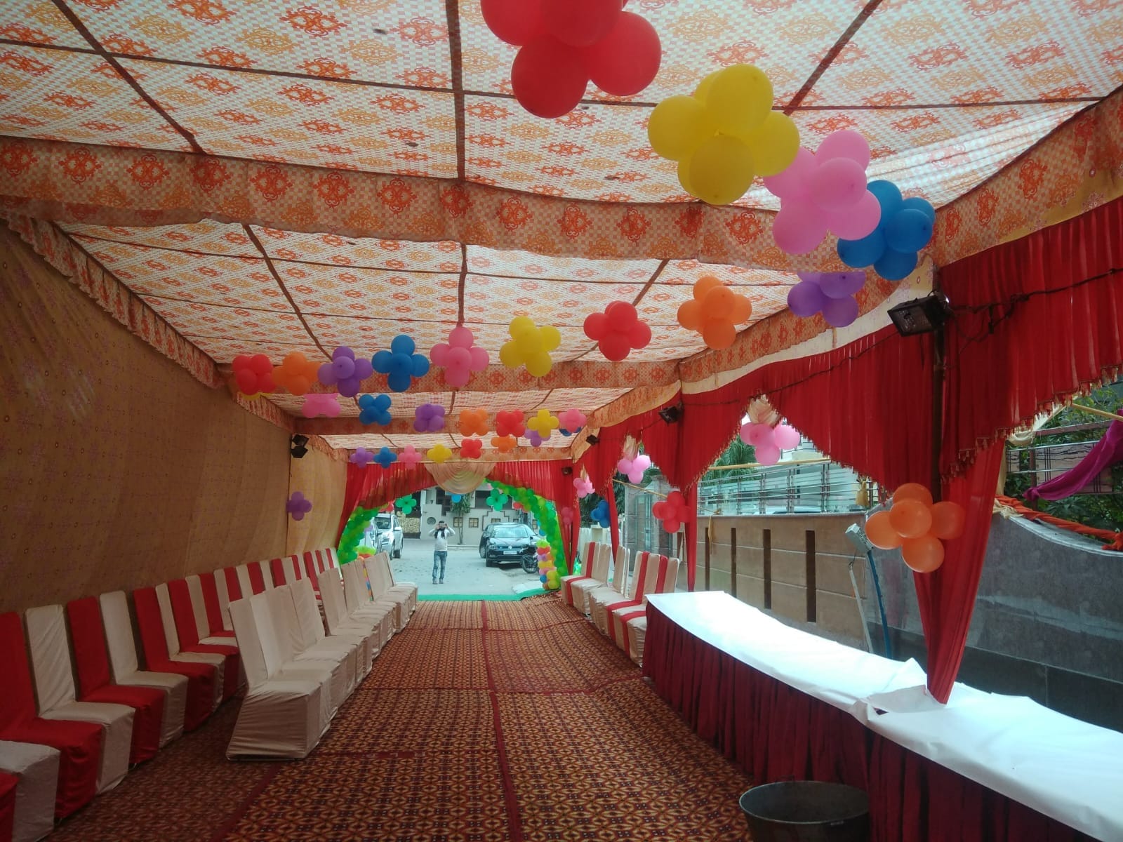 Long covered passage tent with a printed ceiling, red side curtains and balloon flowers along the walls