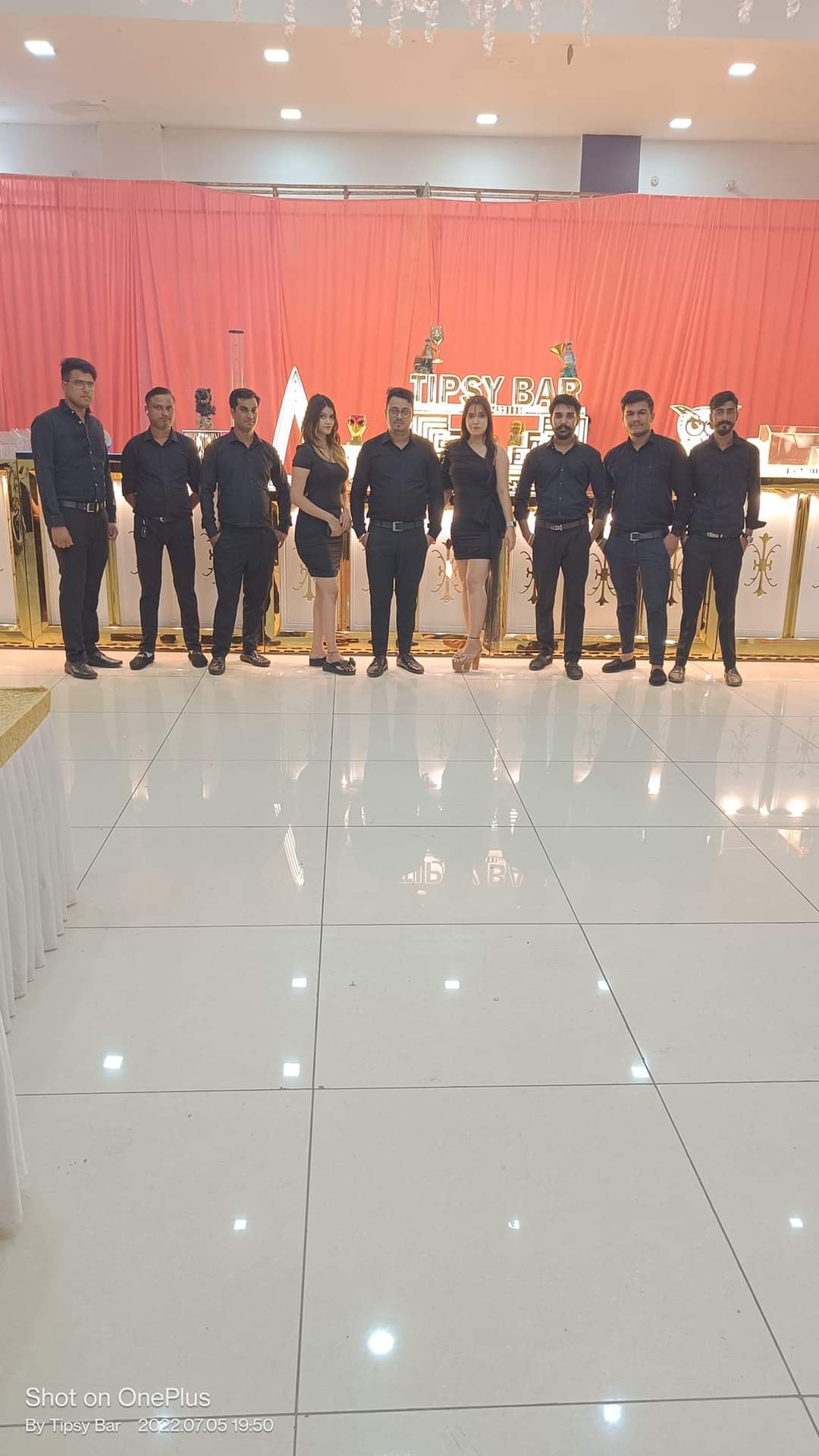 The Tipsy Bar bartending team in black uniforms standing in front of the mobile bar counter