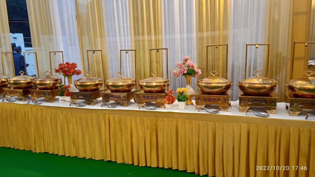 A row of hammered brass chafing dishes set along a buffet counter