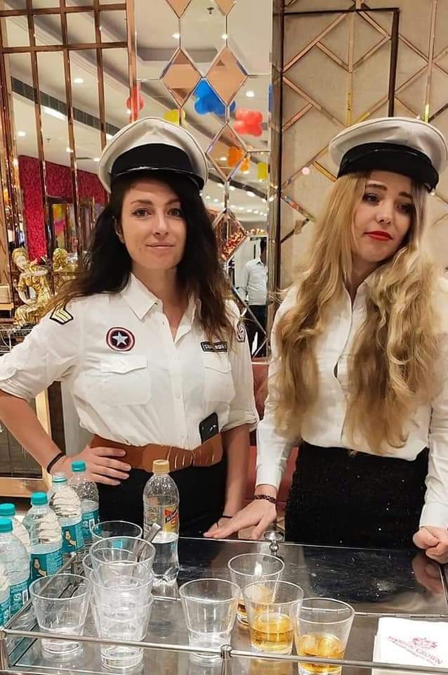 Bartenders in captain uniforms serving welcome drinks from a mobile cart bar