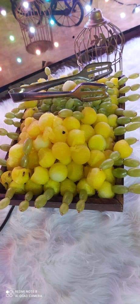 Fruit skewers of melon balls and grapes arranged on a platter with serving tongs