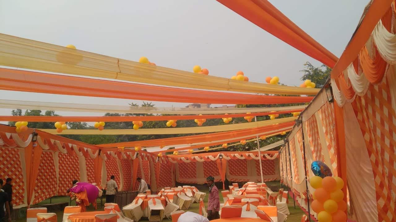 Daytime event tent with orange and yellow ceiling drapes above the dining seating
