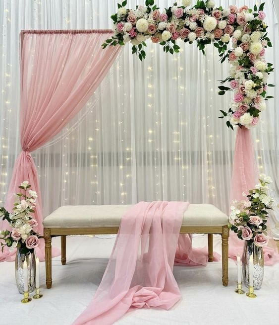 Stage backdrop of pink drapes and fairy lights behind an upholstered bench