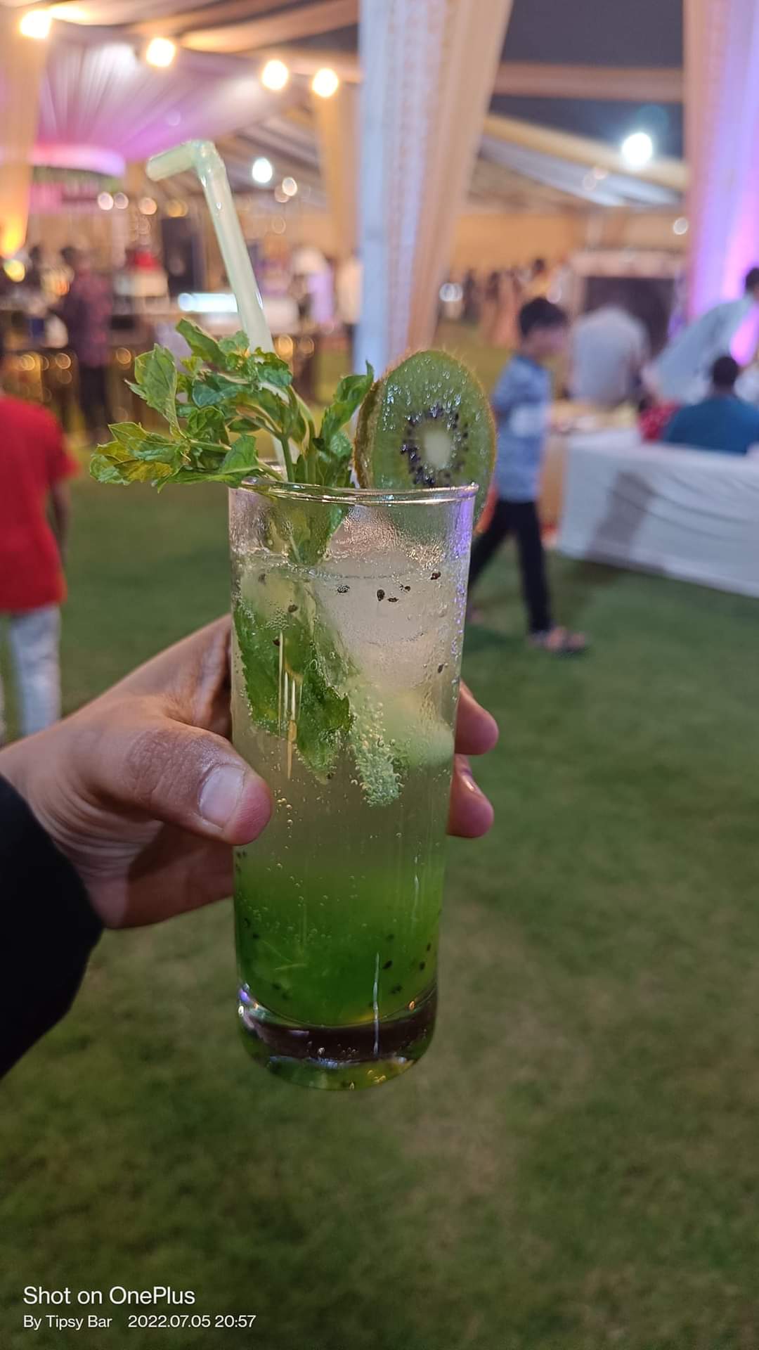 A chilled kiwi and mint mojito held up at an outdoor event