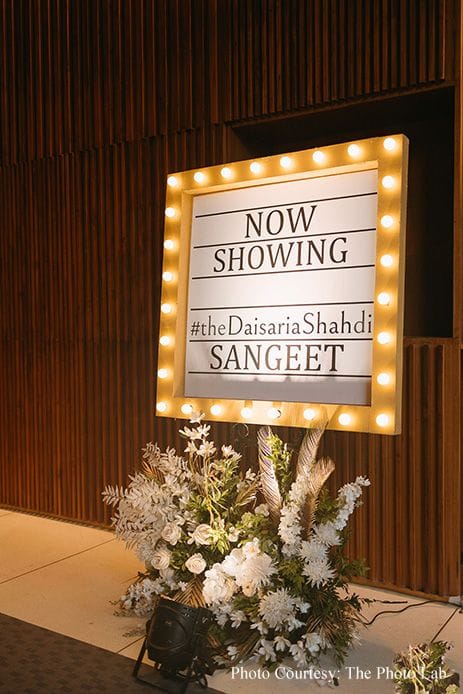 Marquee bulb light board reading NOW SHOWING, set up for a sangeet